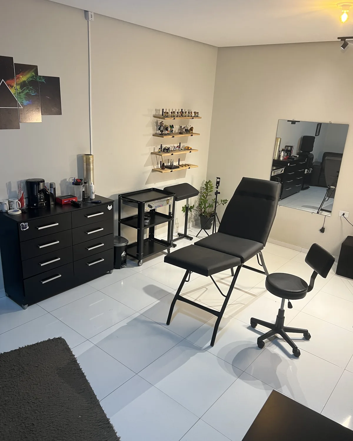 Outro ângulo da sala de tatuagem, com a estação de trabalho e o espelho