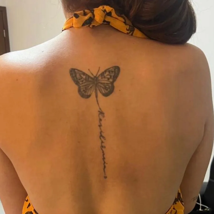 Tatuagem antiga de borboleta em contorno nas costas, borrada pelo tempo, antes da cobertura