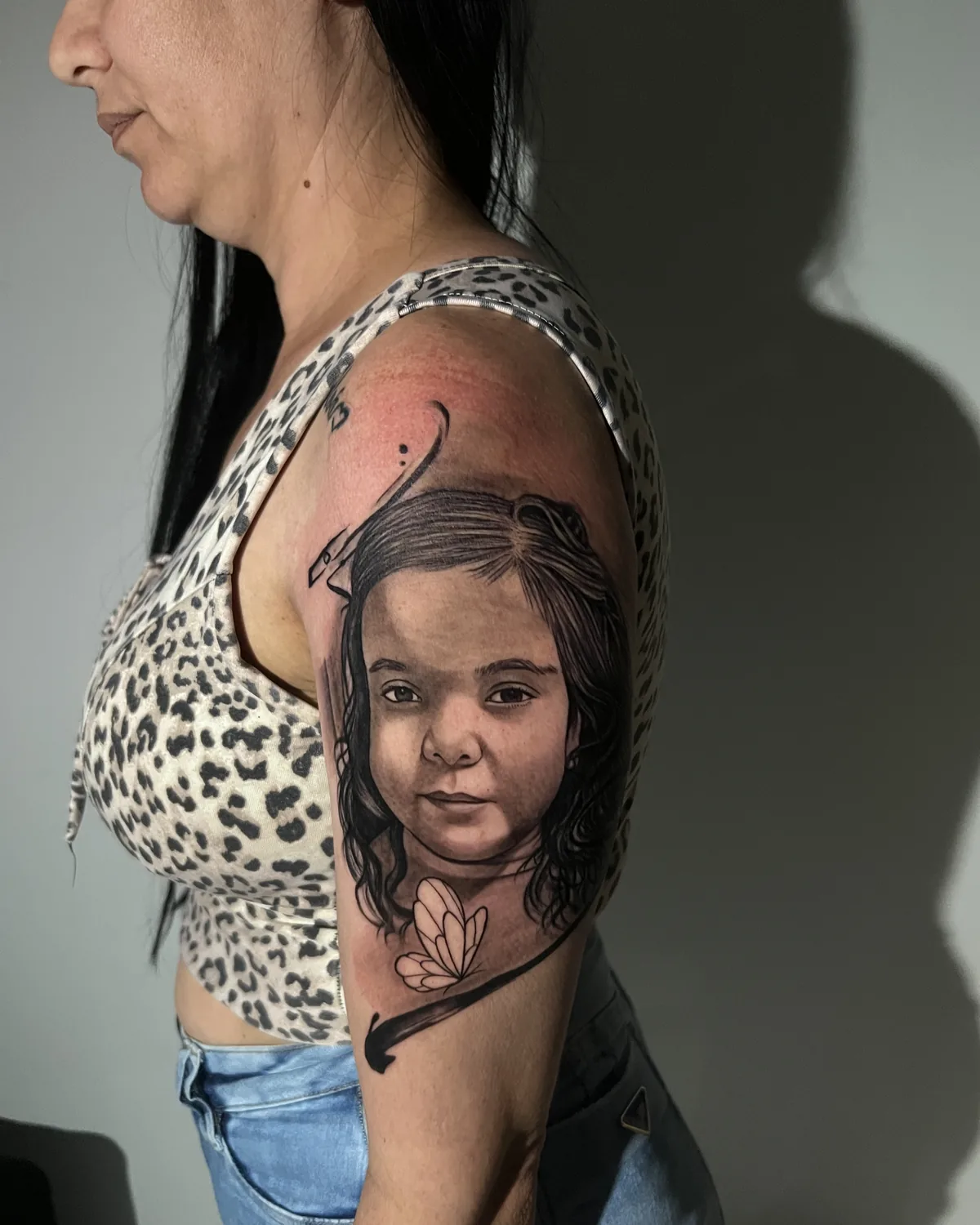 Tatuagem de retrato realista de uma criança no ombro, preto e cinza